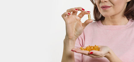 A woman holding an omega 3 capsule choosing Omega 3 Fish Oil Supplement for her