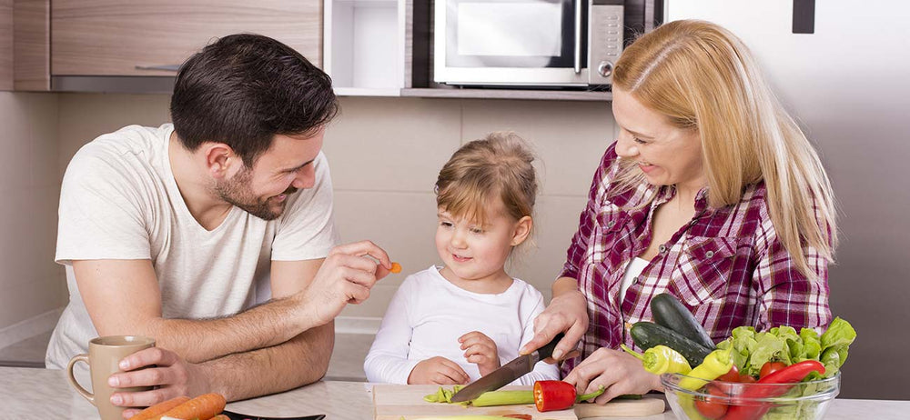 Kid having vitamins and minerals in the form of nutritional vegetables and supplements with parents