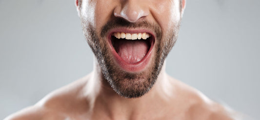 A man's mouth is open, showing healthy gums and teeth by maintaining proper oral health and oral care.